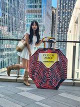 Model standing beside an oversized red Fleur Noir perfume bottle in the TEBO DAMBE® fragrance campaign.
